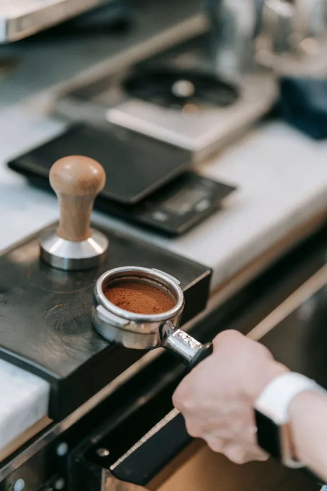 Close-up of barista preparing espresso with a portafilter in a modern coffee shop environment.