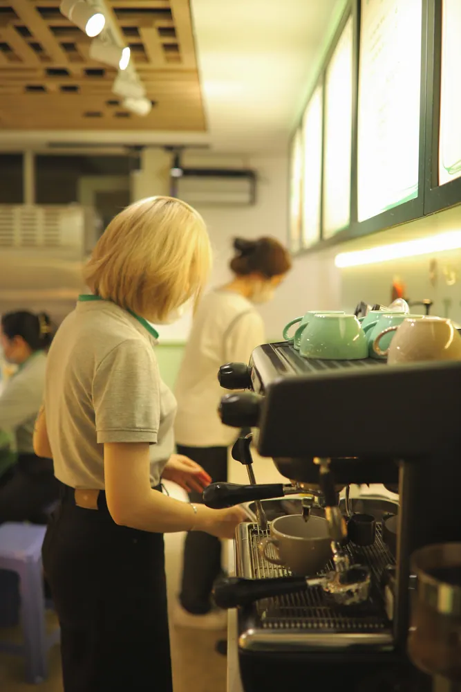 Two baristas preparing coffee in a warm and inviting café environment.