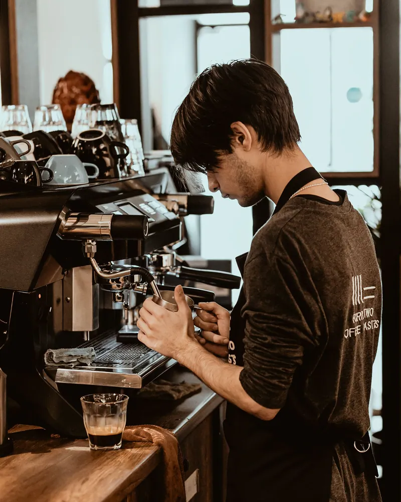 Barista focused on making coffee in a Baku café with modern espresso machine.