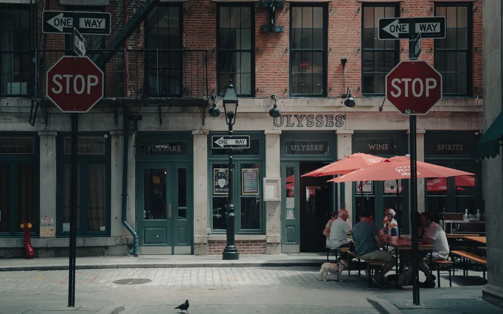 Cafegoers enjoy a sunny day on a cobblestone street at Ulysses in NYC.