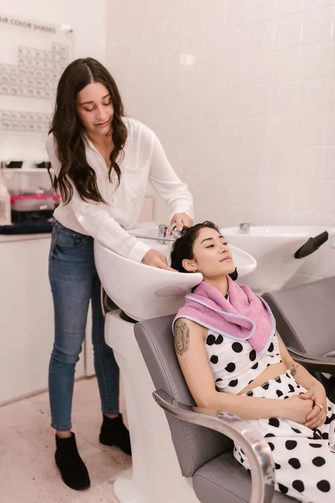 A hair stylist washing a female client's hair at a salon, showcasing a relaxing and professional experience.