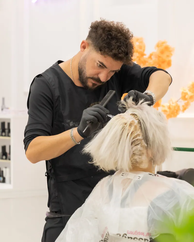 Hair stylist applying hair dye to client in a bright, modern salon setting.