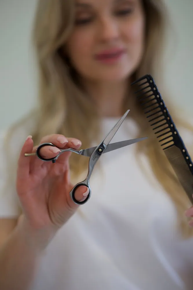 Professional hair stylist with scissors and comb, ready for a haircut.