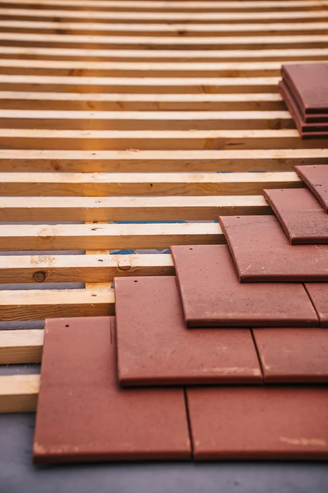 Red roofing tiles and wooden framework in progress on a building roof.